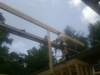 Carpenter setting a ridge beam over a new addition frame — Ice Dam Removal by Roofing Brothers in Vaughn
