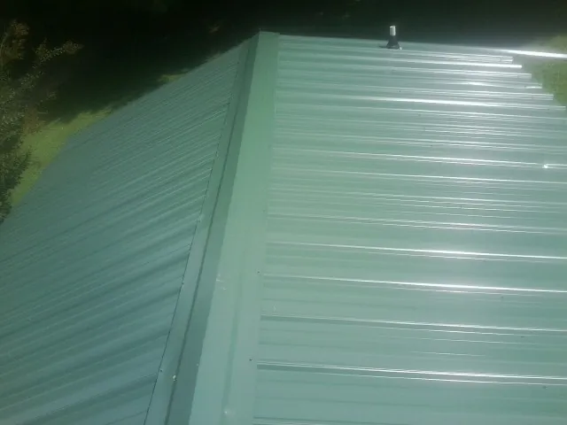 New green metal panels meeting at the ridge of a roof — Flat Roof Repair work by our crew in Vaughn