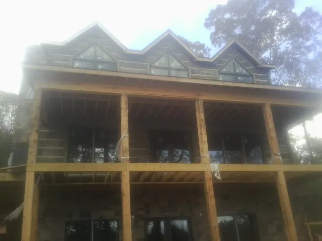 Dormers and porch framing on a large log home under construction — Roof Coating work by our crew in Vaughn