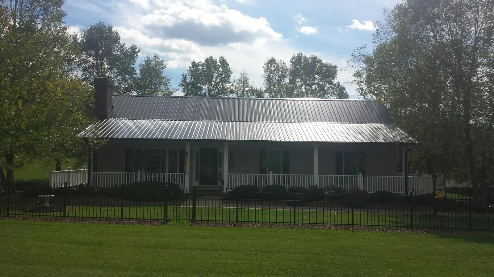 Gray metal roof on a brick ranch with a full width front porch — Gutter Guard Installation work by our crew in Vaughn