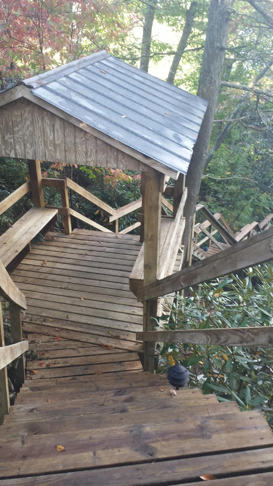Metal roofed shelter over wooden steps on a wooded walkway — Skylight Repair & Installation work by our crew in Vaughn