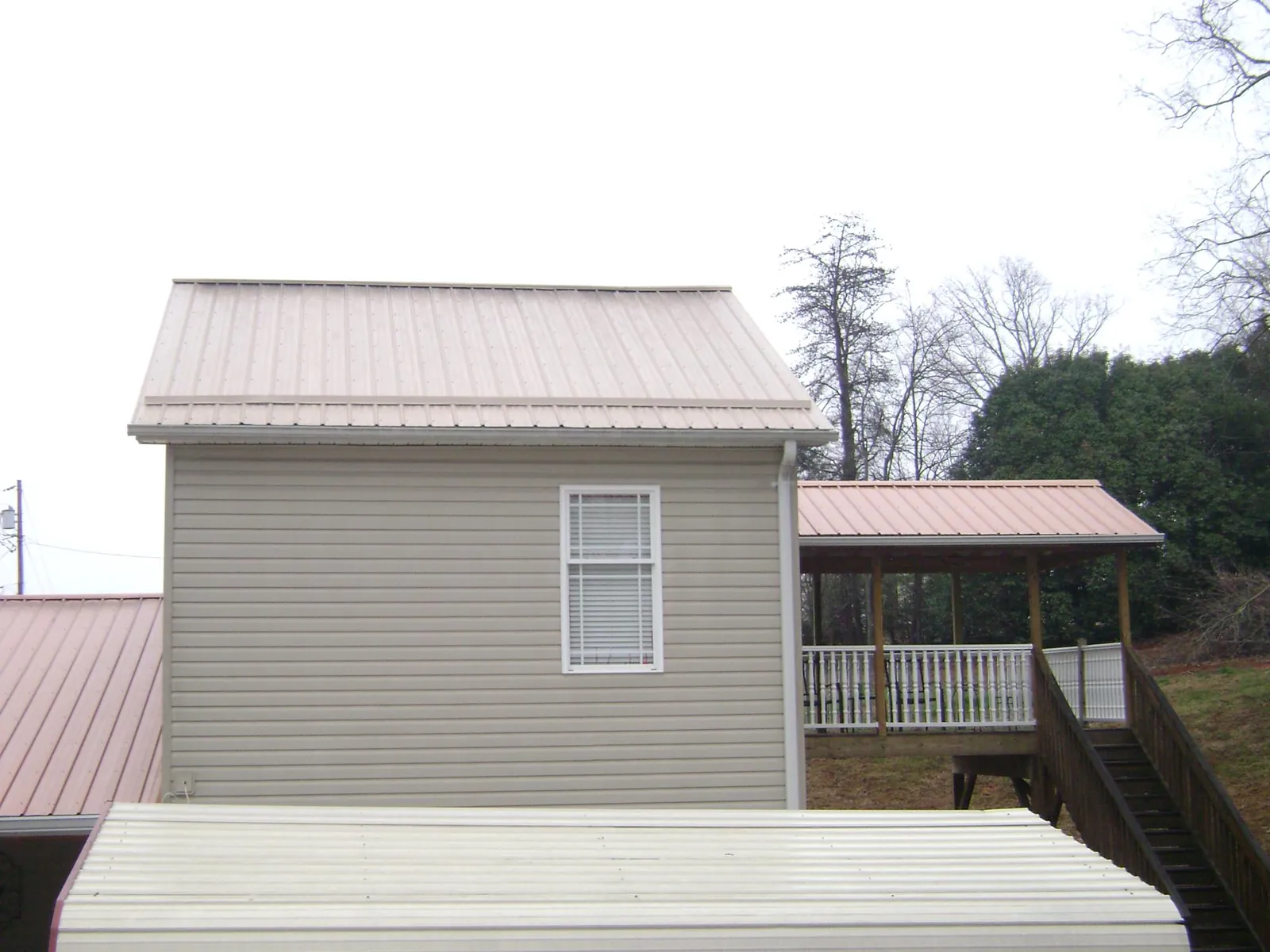 Tan metal roofs on a two story addition and attached porch, from a Roof Replacement job in Vaughn