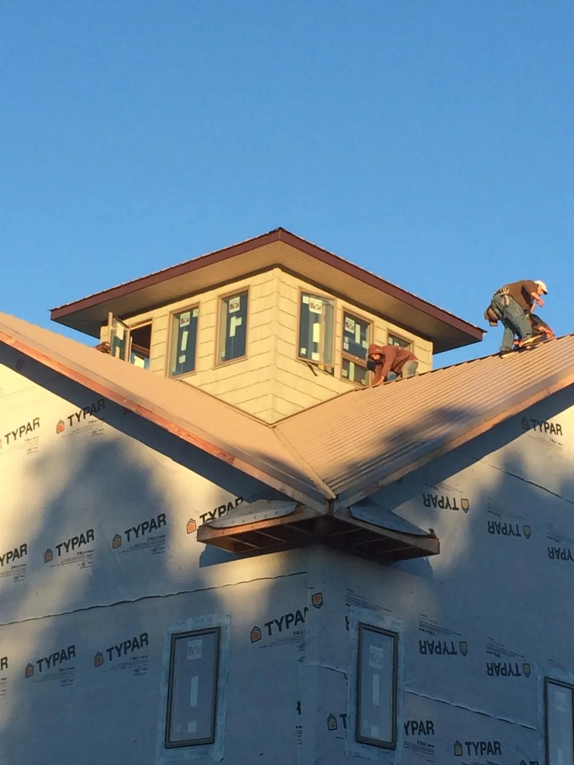 Roofers working around a rooftop cupola on a new metal roof at sunset — Roof Waterproofing in Vaughn by Roofing Brothers